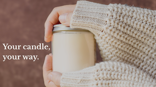 A person in a chunky cream knit sweater holds a glass candle jar with cream-colored wax against a warm brown textured background. White text on the left reads, 'Your candle, your way.'
